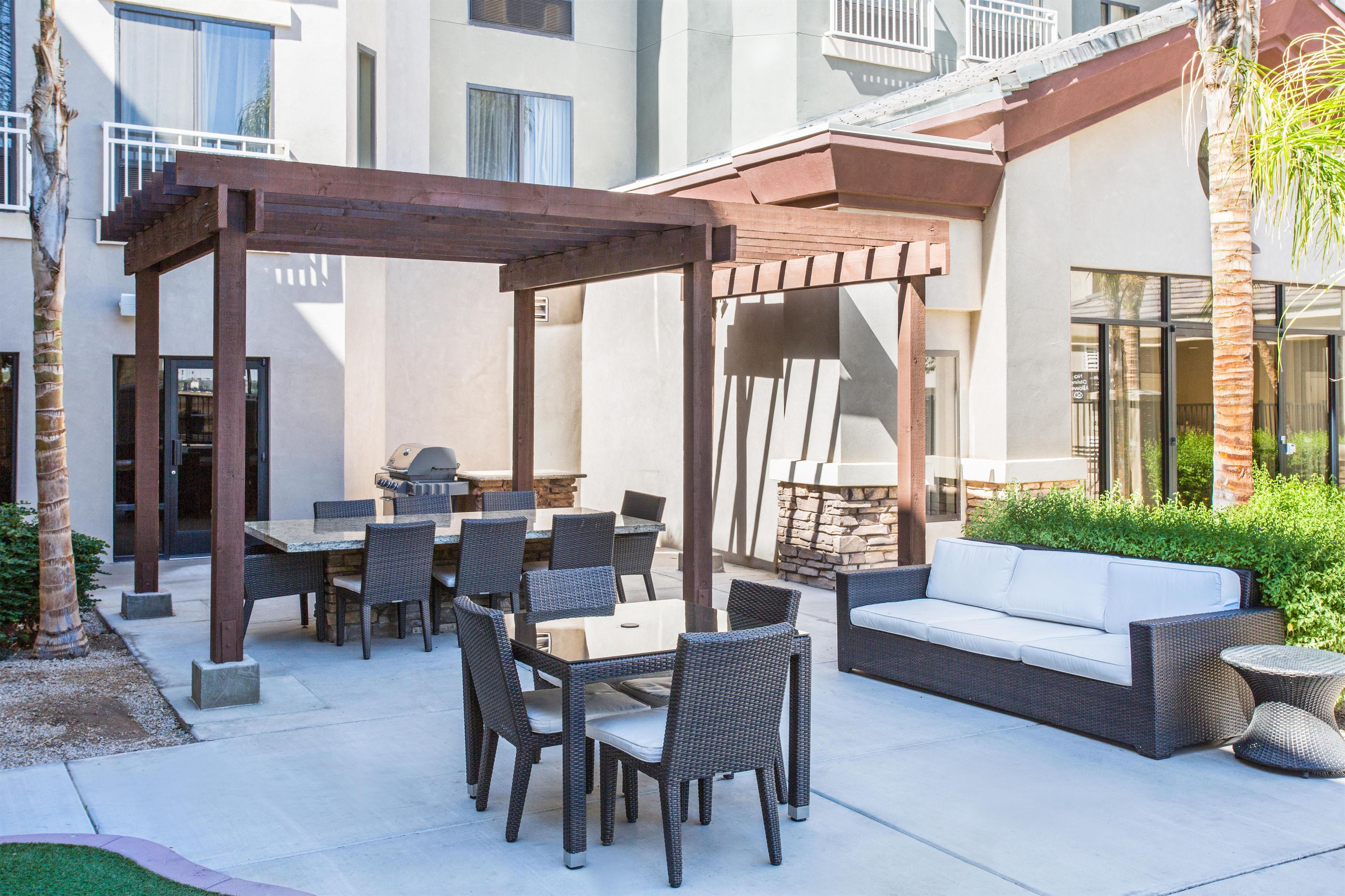 An outdoor patio with a pergola, dining table, chairs, and a sofa.