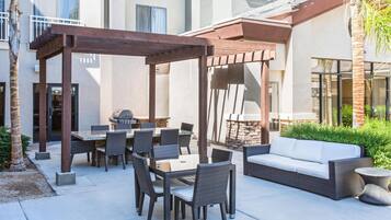 An outdoor patio with a pergola, dining table, chairs, and a sofa.