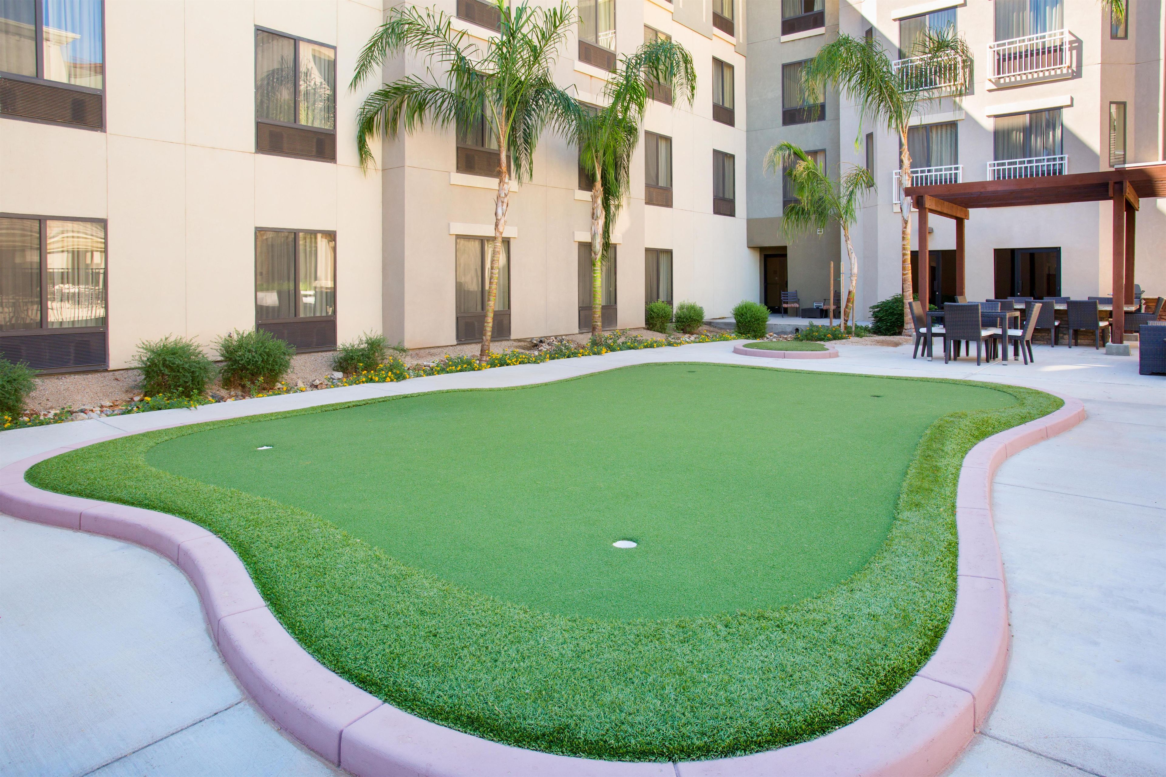 A courtyard with artificial grass, a pool, and outdoor seating.