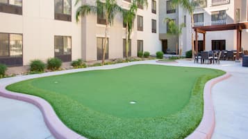 A courtyard with artificial grass, a pool, and outdoor seating.