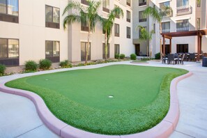A courtyard with artificial grass, a pool, and outdoor seating.