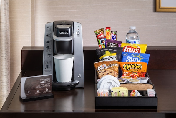 A coffee maker, a tray of snacks, and a water bottle on a hotel counter. - Homewood Suites Phoenix Avondale (Avondale)