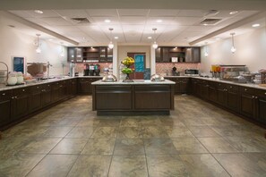 A spacious kitchen with a central island, equipped with various appliances and a buffet setup. - Homewood Suites Phoenix Avondale (Avondale)