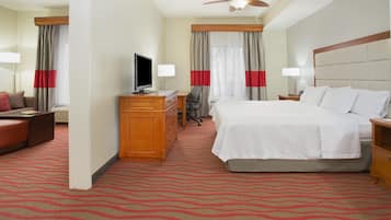 A hotel room with a bed, desk, chair, television, and a ceiling fan.