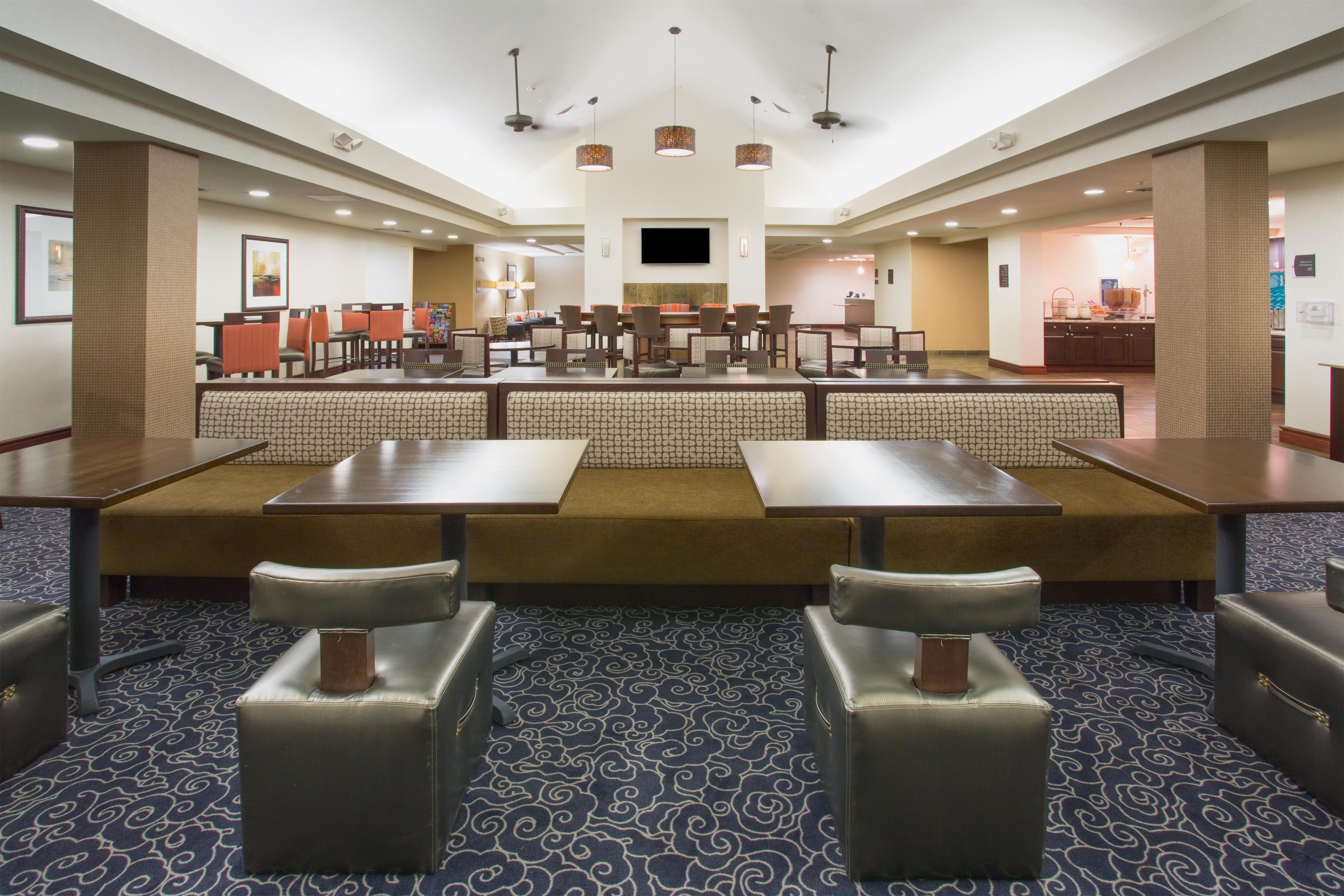Una hall d'albergo con angolo salotto, uno schermo televisivo e la reception.