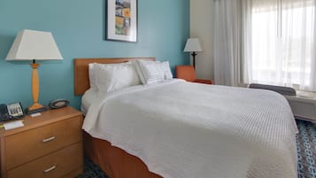 Una habitación de hotel con una cama, lámparas de noche, una mesita de noche con teléfono y una ventana con cortinas.