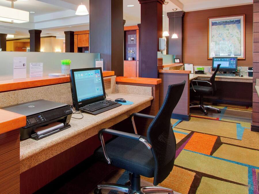 A hotel reception area with a computer, printer, and a desk with a chair.