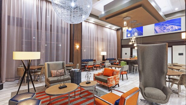 A modern hotel lobby with a seating area, a bar, and a large screen displaying a cityscape. - Hampton Inn & Suites Houston-Bush Intercontinental Aprt (Houston)