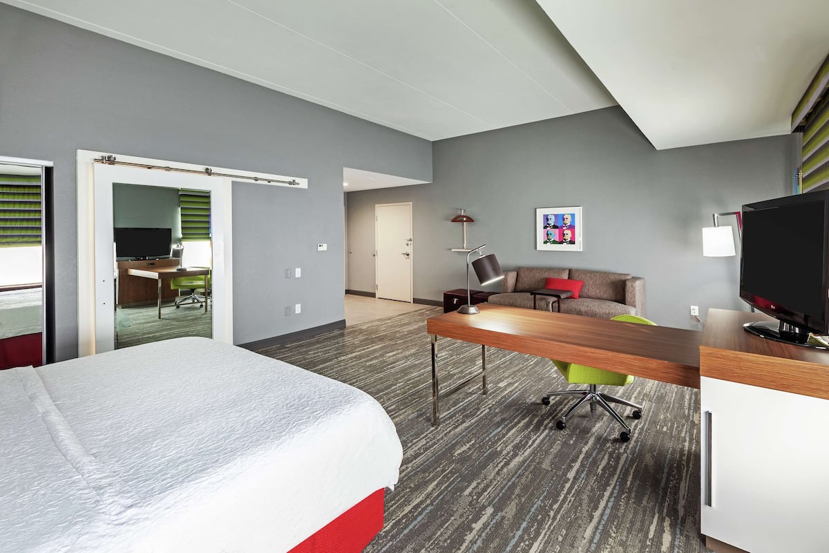 A hotel room with a bed, a desk, a television, and a chair.