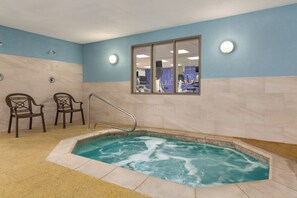 A spa room with a hot tub, two chairs, and a window with a view of exercise equipment. - Holiday Inn Express & Suites Tooele by IHG (Tooele)