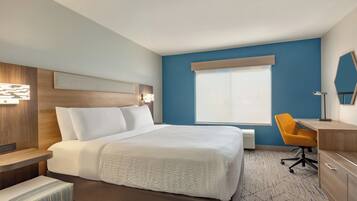 A hotel room with a bed, a desk, a chair, and a window.