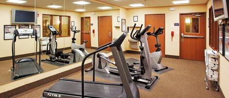 A fitness center with treadmills, elliptical machines, and a mirrored wall.