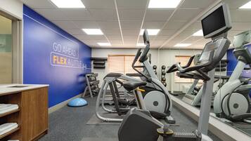 A gym with exercise equipment, a blue wall with motivational text, and a wooden cabinet.