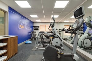 A gym with exercise equipment, a blue wall with motivational text, and a wooden cabinet. - Holiday Inn Express & Suites Tooele by IHG (Tooele)