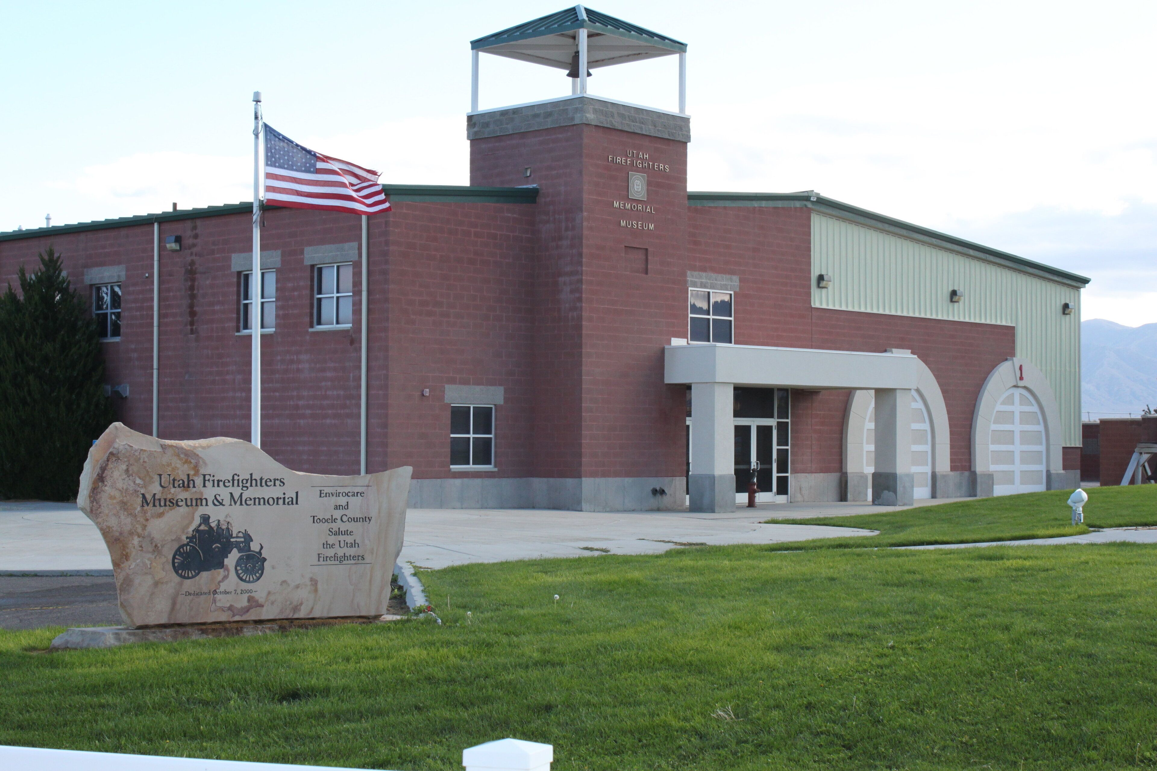 A building with a flag, a sign, and a grassy area.