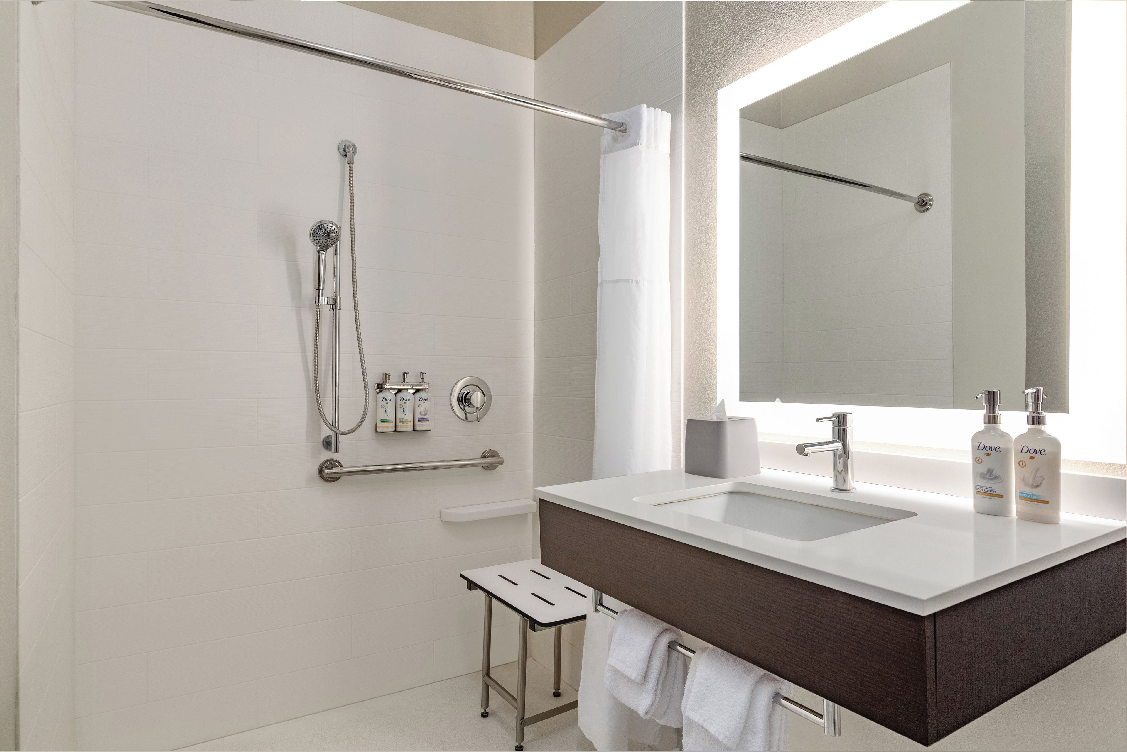 A modern bathroom with a shower, a vanity with a mirror, and toiletries.