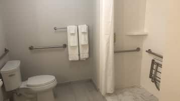 Un baño con inodoro, cortina de ducha y barras de apoyo.