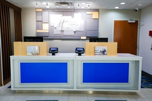 Uma receção com detalhes em azul, dois totens digitais e um aviso com a inscrição 'Hold on Express'.