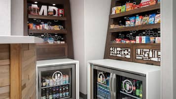 A snack and beverage kiosk with shelves stocked with various snacks and drinks, and two refrigerated beverage dispensers.