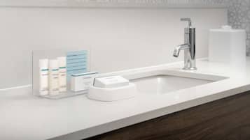A bathroom with a white sink, a mirror above it, and a soap dispenser on the counter.