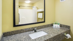 A bathroom with a granite countertop, a white sink, a mirror, and a towel rack with folded towels.