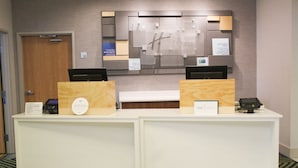 A hotel reception desk with a digital check-in system, a guest card, and a sign indicating check-in and check-out times.