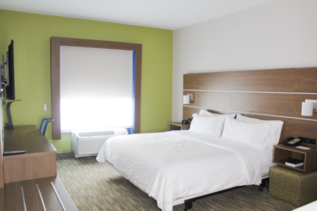 A hotel room with a bed, bedside tables, a desk, and a chair.