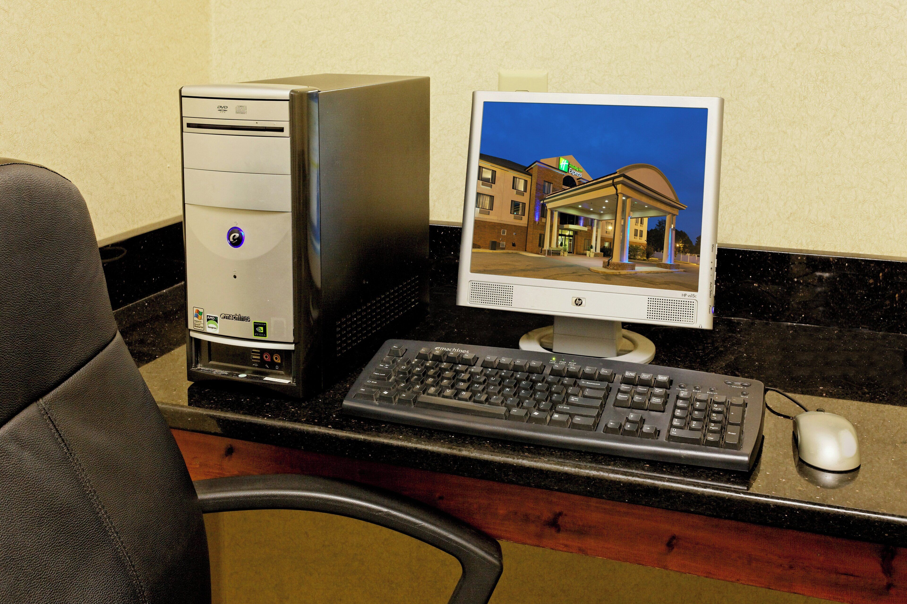 A desktop computer setup with a monitor displaying a building exterior, a keyboard, and a mouse on a desk.