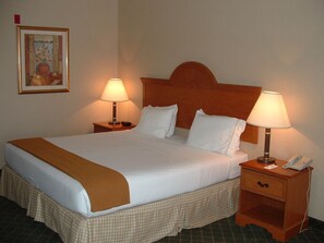 A neatly made bed with a brown throw blanket, two bedside lamps, a bedside phone, and a small wooden nightstand. - Holiday Inn Express Hotel & Suites Sylacauga by IHG (Sylacauga)