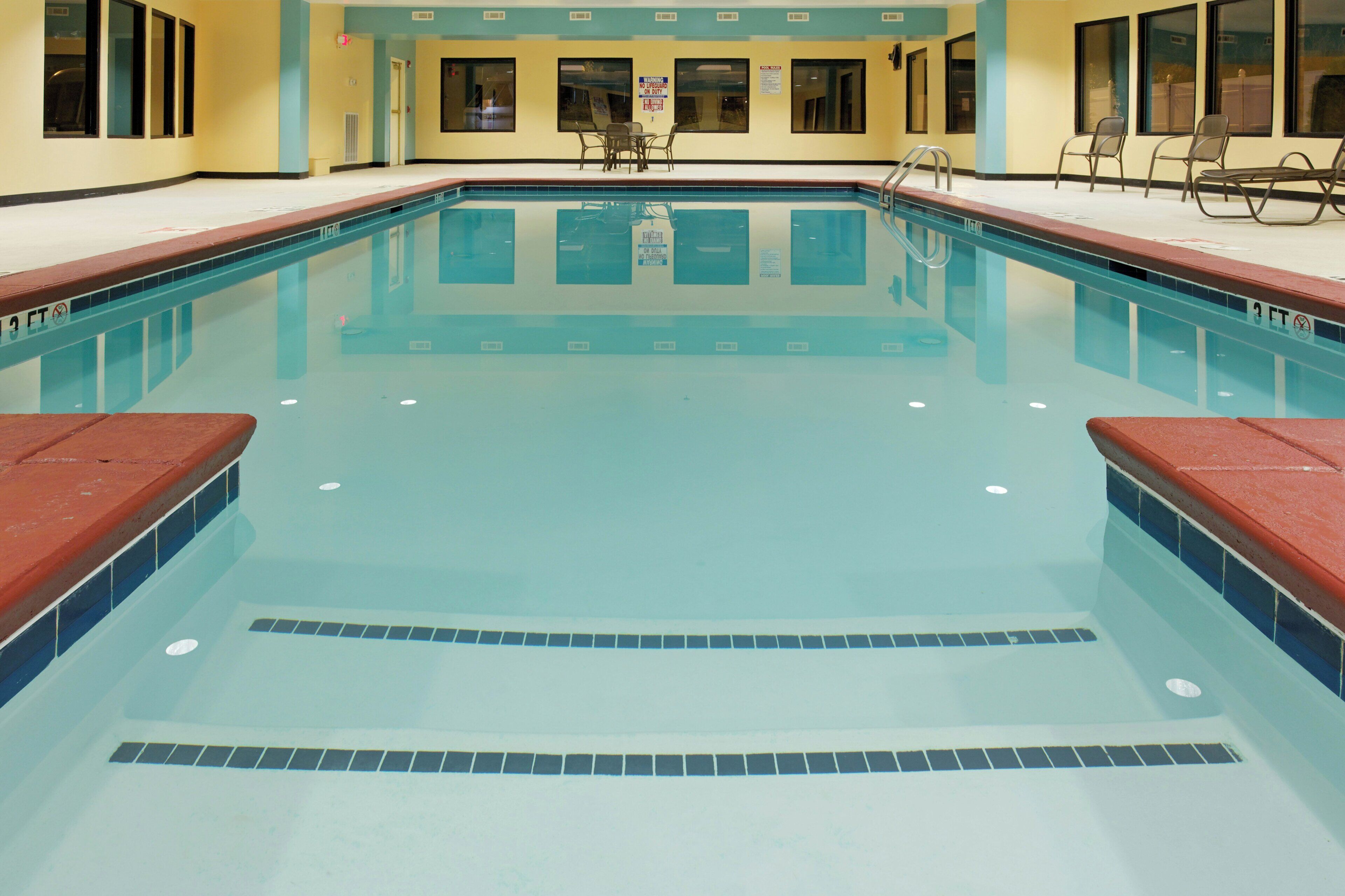 Una piscina con borde de azulejos, una silla de salvavidas y un letrero que indica 'no buceo'.
