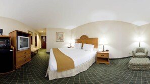 A hotel room with a large bed, two bedside tables with lamps, a television, a small cabinet, and a chair. - Holiday Inn Express Hotel & Suites Sylacauga by IHG (Sylacauga)