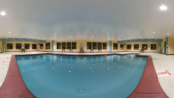 A large indoor swimming pool with clear water, surrounded by lounge chairs and a few tables. - Holiday Inn Express Hotel & Suites Sylacauga by IHG (Sylacauga)