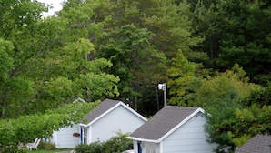 A row of small, single-story cabins with a gravel driveway leading to the entrance. Each cabin has a door and windows, and there are chairs and a car parked outside. - Isleview Motel and Cottages (Trenton)