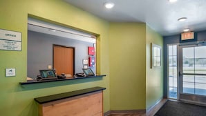 A reception area with a check-in counter, a wooden desk, a mirror, and an exit sign.