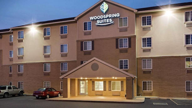 A multi-story hotel with a prominent sign reading "Woodspring Suites." - WoodSpring Suites Fort Worth Fossil Creek (Fort Worth)