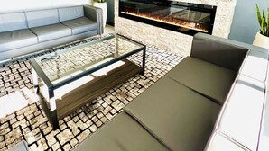 A modern living room with a stone wall, a flat-screen TV, a fireplace, and a seating area with a glass coffee table. - Quality Inn & Suites Caribou (Caribou)