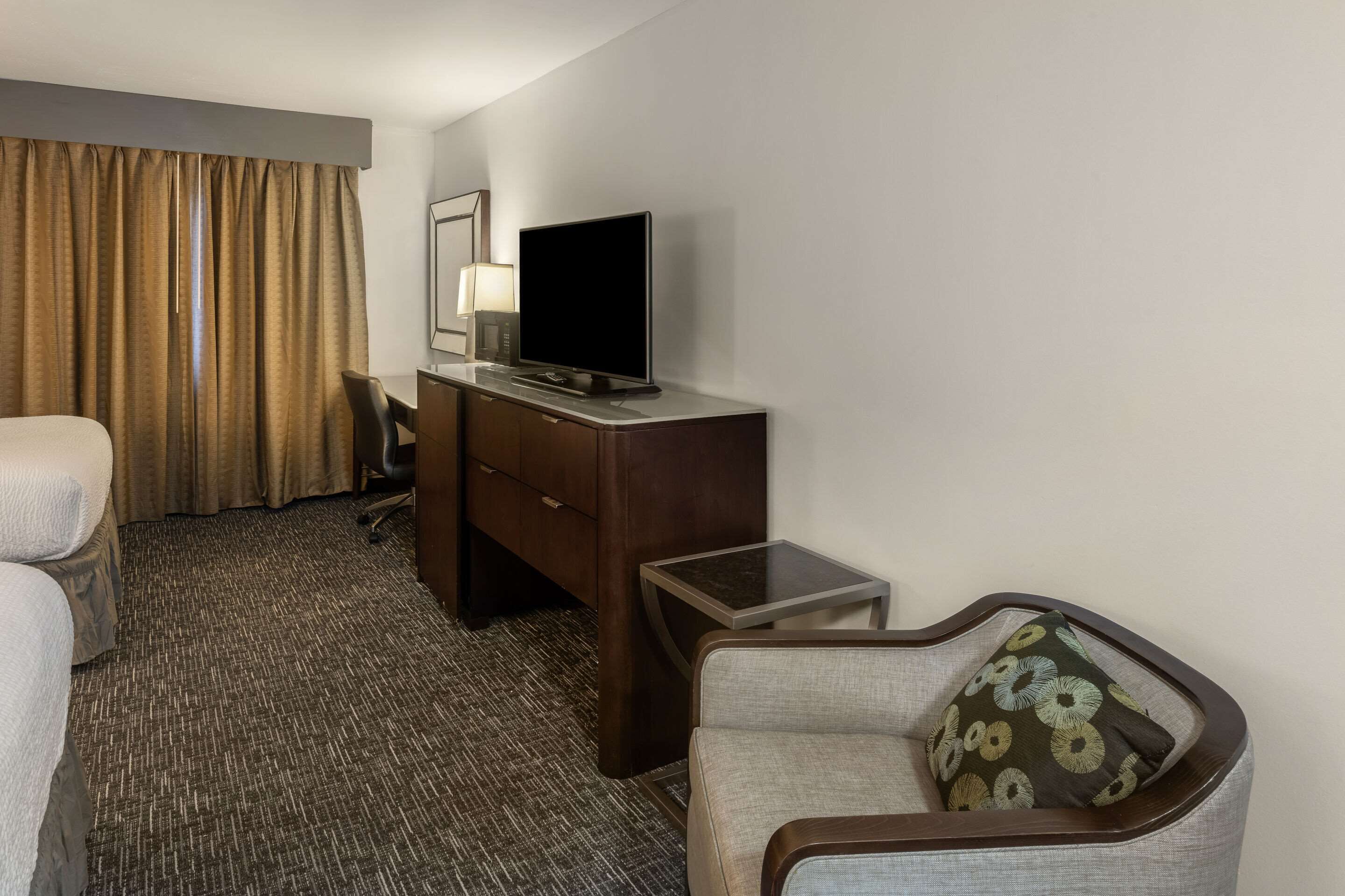 Een hotelkamer met een bed, een bureau met televisie, een stoel, een klein tafeltje en een bank.