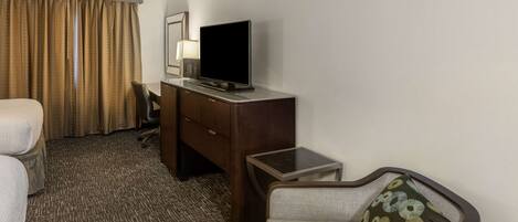 Een hotelkamer met een bed, een bureau met televisie, een stoel, een klein tafeltje en een bank.