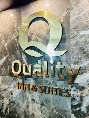 A sign with the logo and name 'Quality Inn & Suites' on a marble background.