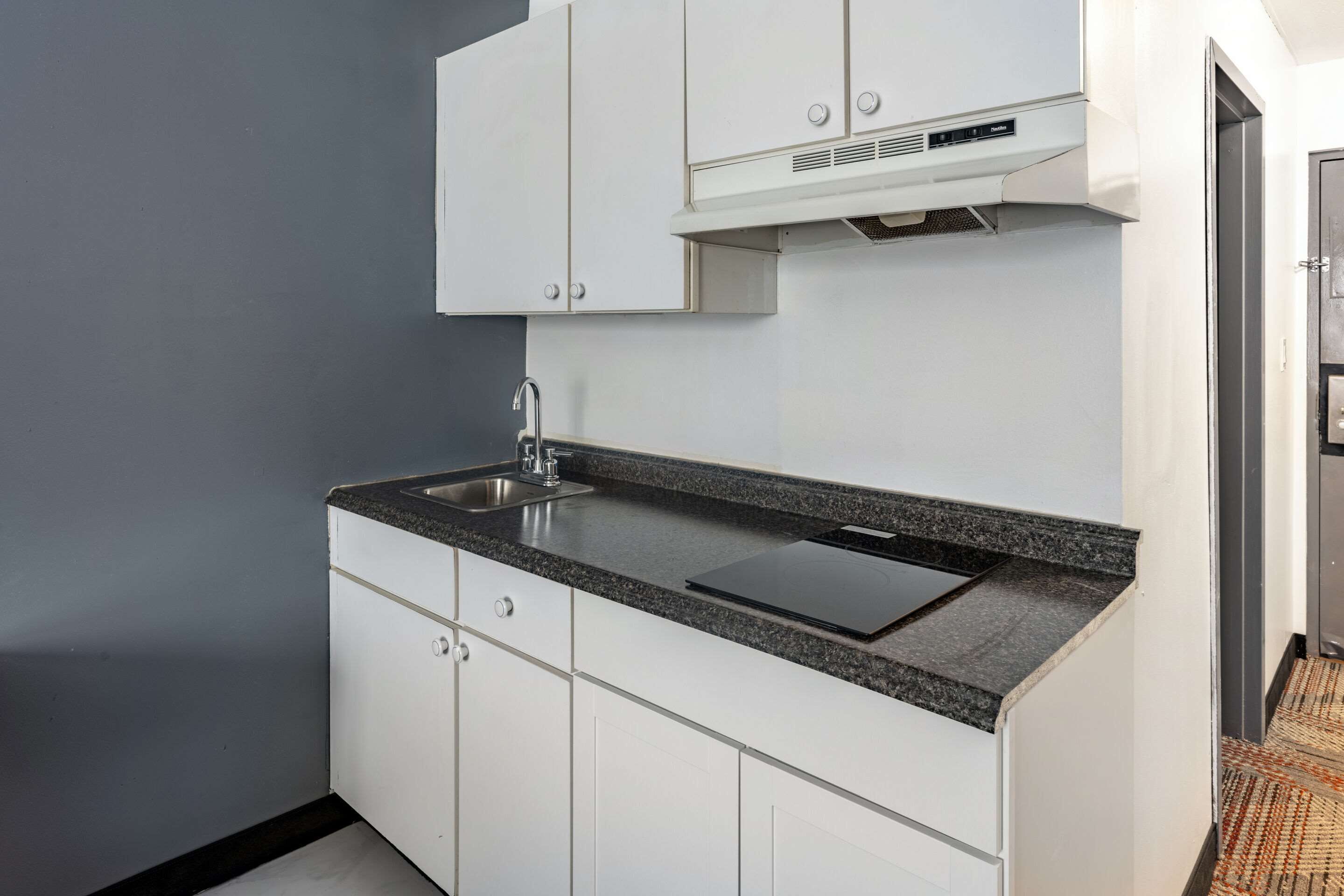Een moderne keuken met witte kasten, een granieten aanrechtblad en een inbouwfornuis.
