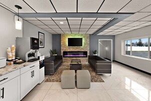 Una sala de estar moderna con chimenea, zona de estar y encimera de cocina con cafeteras.