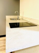Una cocina con un lavamanos moderno y una encimera negra.
