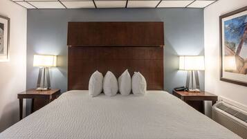A hotel room with a large bed, a wooden headboard, two bedside tables with lamps, and a framed picture on the wall.