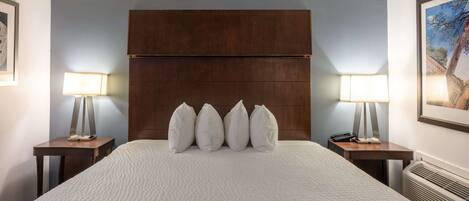 A hotel room with a large bed, a wooden headboard, two bedside tables with lamps, and a framed picture on the wall.