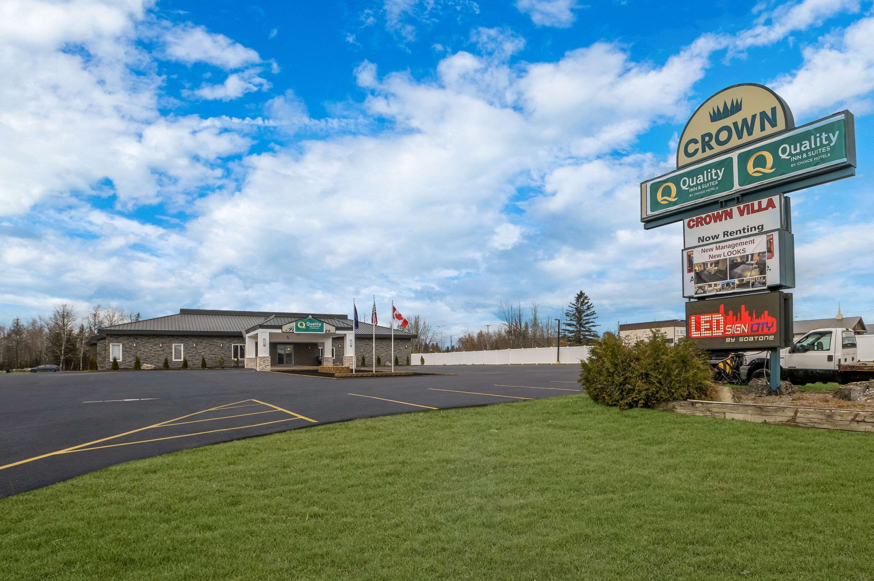 A hotel sign with "Crown Quality" and "Crown Villa" branding, a parking lot, and a building with a stone facade.