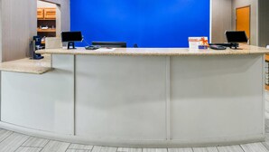 A reception desk with two computer monitors, a blue wall, and a wooden door in the background. - Comfort Suites Ardmore (Ardmore)