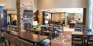 A hotel lobby with a stone fireplace, seating area, and a bar. - Staybridge Suites Fargo by IHG (Fargo)