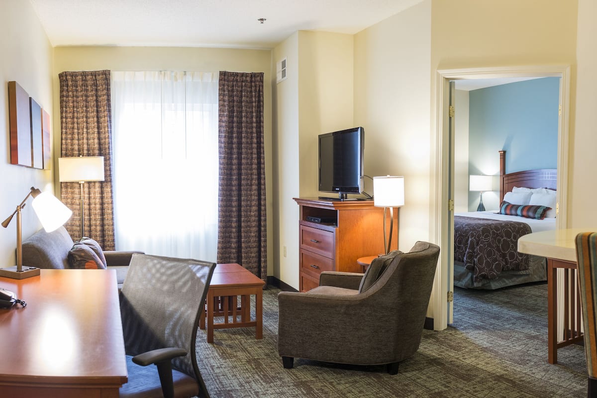 A hotel room with a desk, chair, television, and a bed.