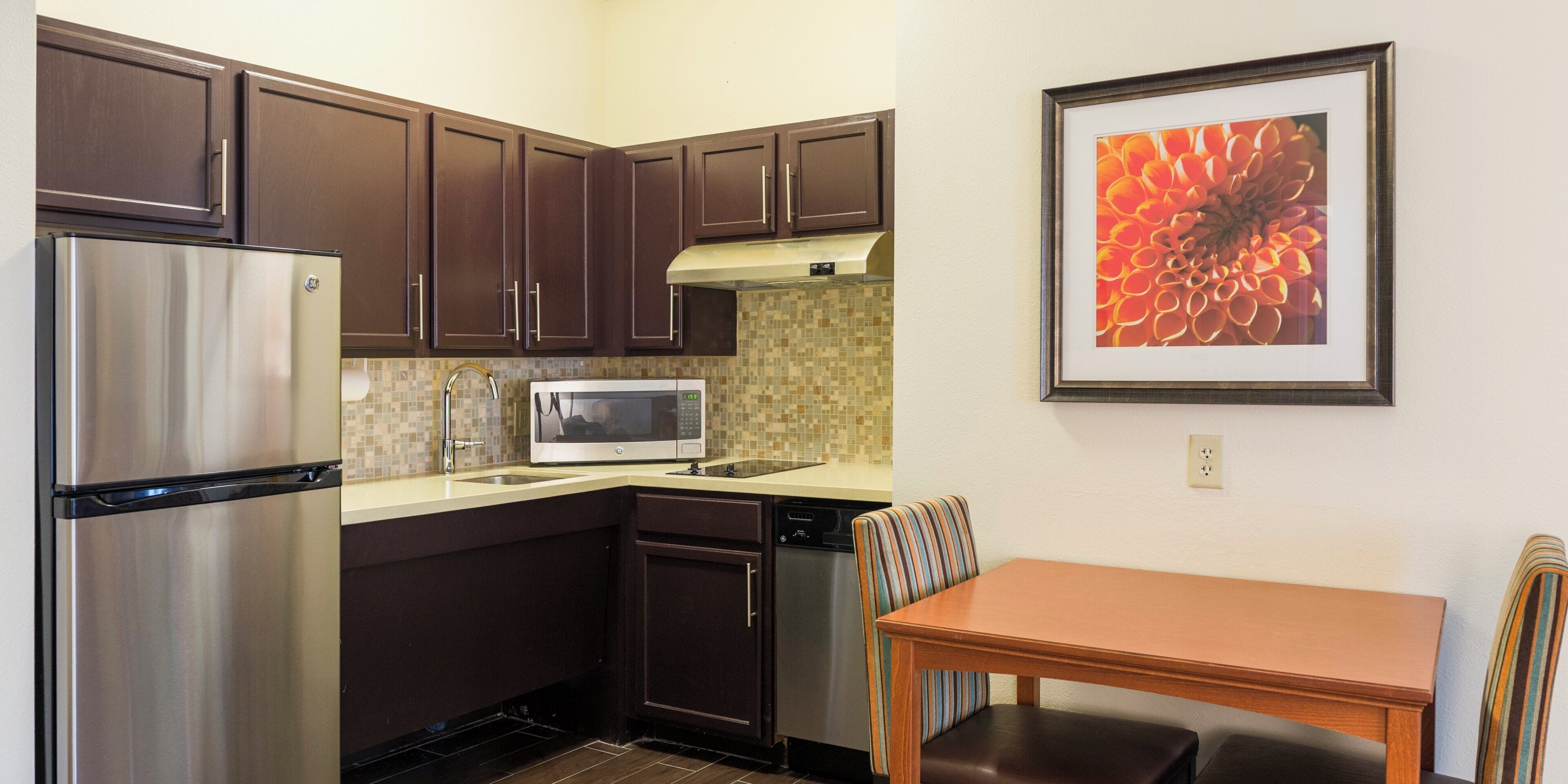 A compact kitchen with a refrigerator, microwave, sink, and a dining area with a table and chairs.