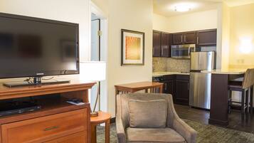 A modern kitchen with stainless steel appliances, a flat-screen TV, and a comfortable seating area with a cushioned chair.